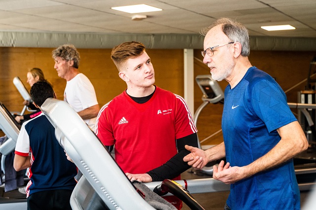 Student helpt meneer op fitnesapparaat